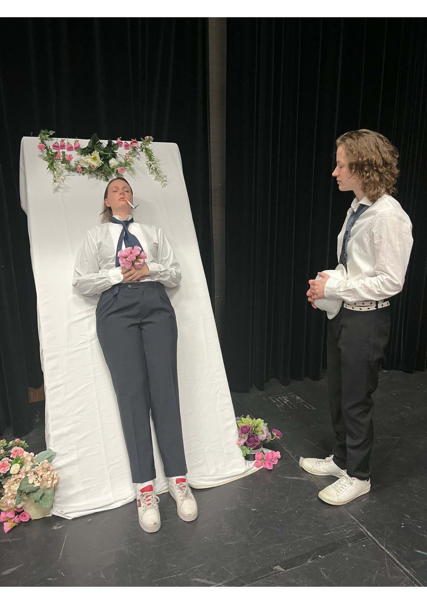 foto van twee personen in zwart witte kleding voor een gordijn en met bloemen